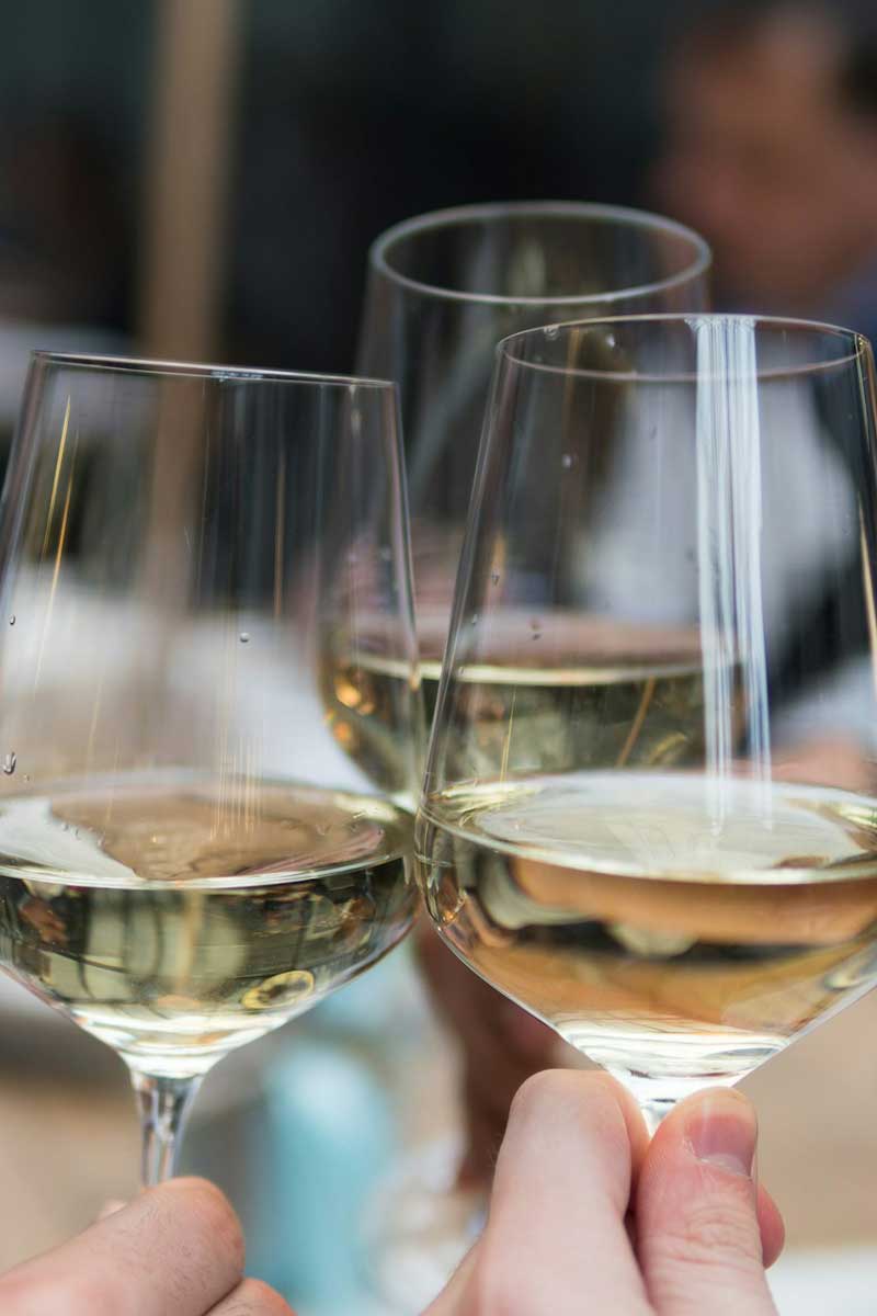 Drei Weißweingläser beim anstoßen
